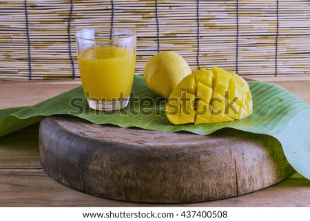 Fresh mango cocktail with mango fruit, bamboo background.