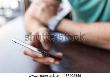close-up of a man who holds in his hand a smartphone . He is sitting in a cafe . business person browsing internet or connecting to wireless via touchscreen pad Royalty-Free Stock Photo #437402656