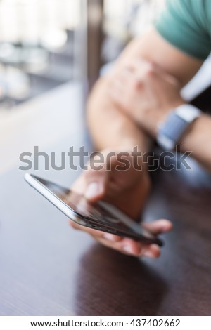 close-up of a man who holds in his hand a smartphone . He is sitting in a cafe . business person browsing internet or connecting to wireless via touchscreen pad Royalty-Free Stock Photo #437402662