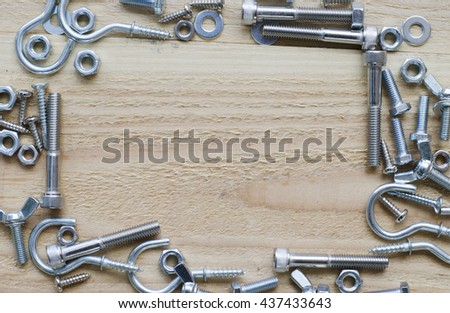Screw hooks and fasteners made of stainless steel on the wood background.