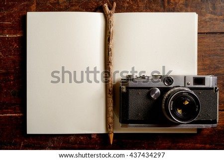The old vintage and grunge cameras with old blank note book on the wooden table. Image made vintage tone and blank space.