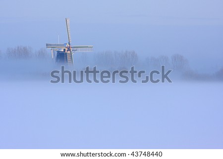 Traditional Dutch windmill in fog and snow.