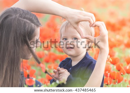 Mother with funny child outdoor at poppy flowers field. Happy Family Values. Baby girl and mom. Mother's care is most important in baby love. Kid. Spring. Children's Day, Mother's Day. Heart symbol