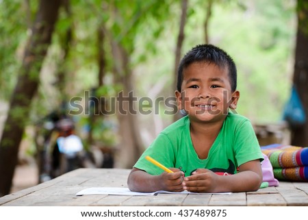 Asian children study at old home. Poor kid learning to drawing, painting with color pencil. Poverty child, smile, lying on dirty wooden table and writing on book. Poor Quality Education Concept