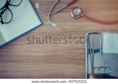 A wooden Desk with a note, glasse equipment wound and a stethoscope with copy space in the middle ,vintage color