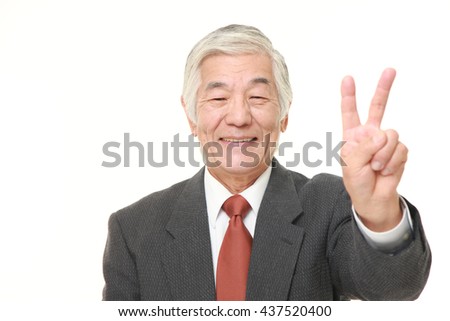 senior Japanese businessman wearing a gray suit showing a victory sign