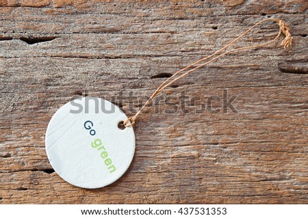 TAG LABEL WITH GO GREEN CONCEPT ON OLD WOODEN TEXTURE BACKGROUND, SELECTIVE FOCUS BLANK COPY-SPACE ON RIGHT TOP VIEW 