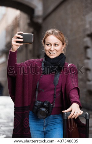 Young cheerful girl taking picture with her phone in the town