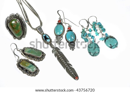 An assorted collection of handcrafted silver and turquoise Native American jewelry isolated on white background.