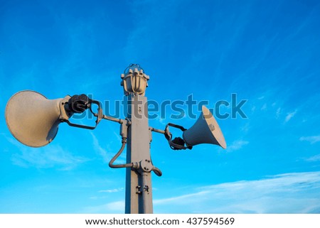 Two loudspeakers and alarm lamp are installed on column against clear sky 