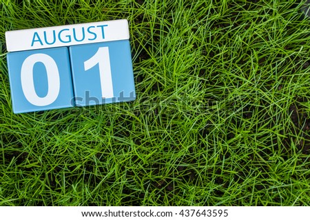 August 1st. Image of august 1 wooden color calendar on green grass lawn background. Summer day. Empty space for text.