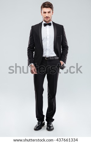 Confident attractive young man in tuxedo standing with hand in pocket Royalty-Free Stock Photo #437661334