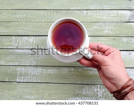 Small cup of tea or coffee in man hand on old  wooden background.
Hipster style.