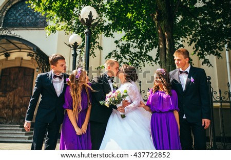 Newlywed couple, bridesmaids & groomsmen having fun outdoors. Bridesmaids in purple (violet) dress. Walking in the city. 