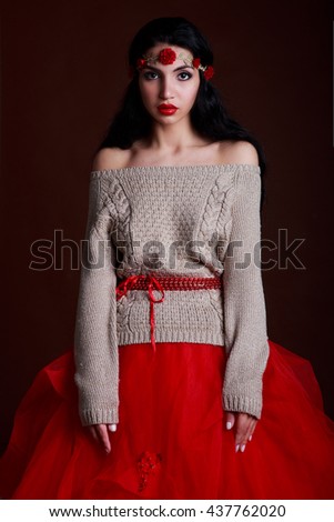 portrait of a beautiful girl in a sweater and red skirt on a dark background