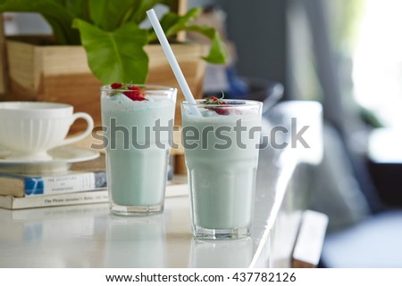 Still Life Profile of Refreshing and Cool Frozen Blue Fruit Slush Drink in Plastic Cup Served on Rustic Wooden Table with Colorful Drinking Straws

