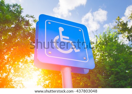 Parking for disability persons sign with green and sun light background.