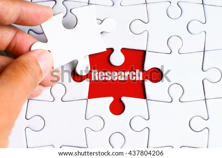 A missing puzzle with a hand hold a piece of "Research" text puzzle want to complete it - business and finance conceptt Royalty-Free Stock Photo #437804206
