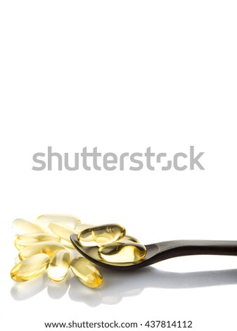 Fish oil supplement capsule with wooden spoon over white background