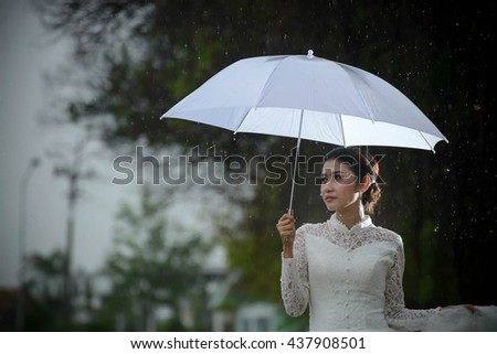 Beautiful bride girl holding white umbrella,white dress,lonely bride standing in raining day