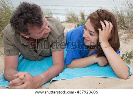 Picture of a man and woman lying on the beach and talking