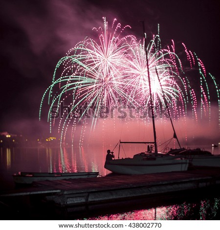 Ignis Brunensis green and pink colored fireworks resembling aster flower reflecting on water surface of dam. Long exposure night graphical photography using creative tilt effect by tilt-shift lens.