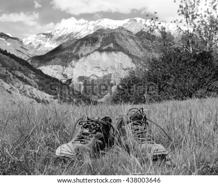 Old hiking shoes and Alpine landscape at background. Provence-Alpes-Cote d'Azur region of France. Black and white photo.