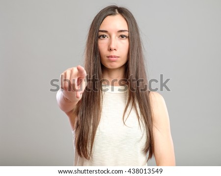 Picture of attractive young woman pointing her finger to viewer isolated on gray