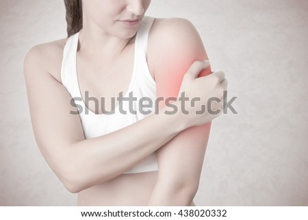 Female with pain in her arm, isolated in a grey background