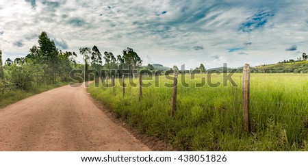 Dirt Road and barbed wire fence on summer afternoon in Minas Gerais Mountains, Brazil Royalty-Free Stock Photo #438051826