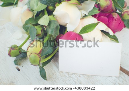Peony background. Fuchsia, pink and white peonies on white wooden table with an empty card for text. Happy Mothers Day. Mother's Day greetings card. Valentines Day. Copy space. Toned image.