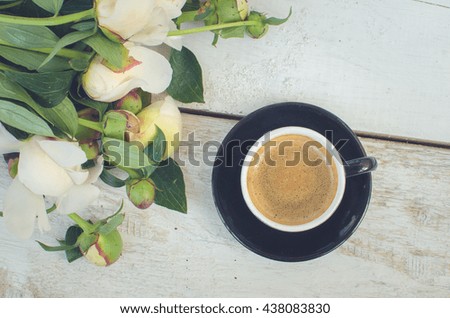 Coffee and flowers peony. A cup of coffee and Peonies on a white wooden table. Breakfast on Mothers day, Valentines Day or Women's day. Spring or summer background. Copy space. Top view. Toned image.