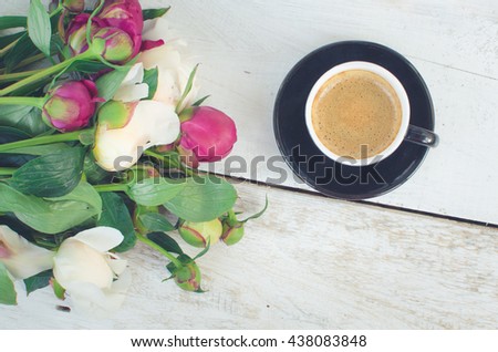 Coffee and flowers peony. A cup of coffee and Peonies on a white wooden table. Breakfast on Mothers day, Valentines Day or Womens day. Spring or summer background. Copy space. Top view. Toned image.