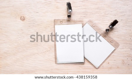 Name tag or identification holder with metal clip on wooden surface. Isolated on empty background. Slightly de-focused and close-up shot. Copy space.