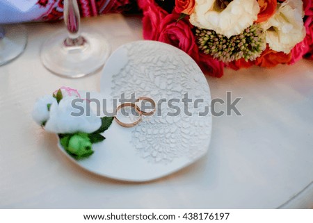 Wedding rings on a decorative plate with flowers