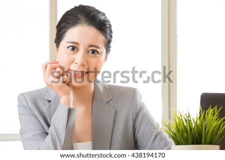 Successful asian female entrepreneur sitting and smiling at desk in office