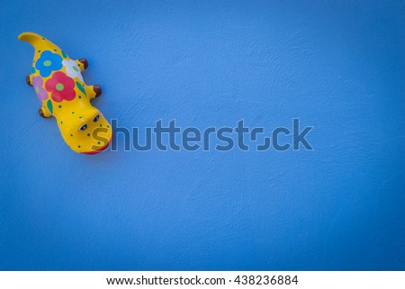 Gecko Doll Model blue background. Toy Lizard on blue cement wall. 