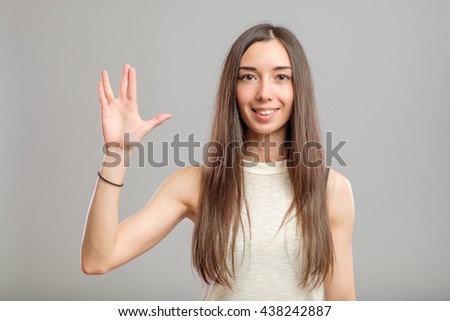 Pretty woman making Vulcan greeting isolated on gray