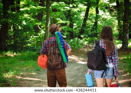 Young couple walking with backpacks in forest. Camping, hiking.
