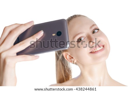 Selfie Attractive young woman holding mobile phone and making photo of herself while standing against white background focused on face