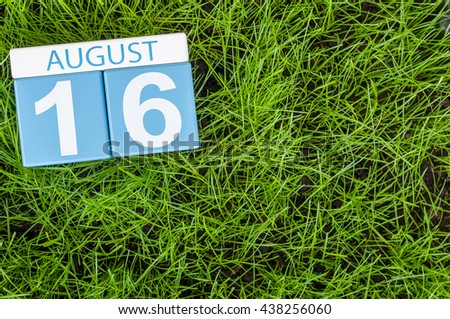 August 16th. Image of august 16 wooden color calendar on green grass lawn background with soccer ball. Summer day. Empty space for text