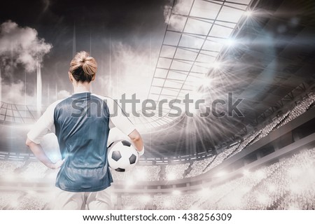 Rear view of woman football player posing against sports arena