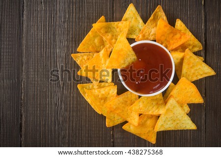 Corn chips  nachos with salsa sauce on a wooden table.
