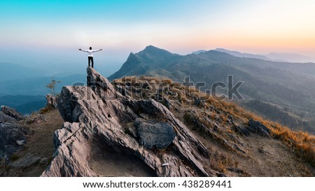 businessman success hiking on the peak of rocks mountain at sunset, winner leader concept Royalty-Free Stock Photo #438289441