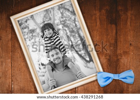 Father carrying a happy son on shoulders at park against white background with vignette