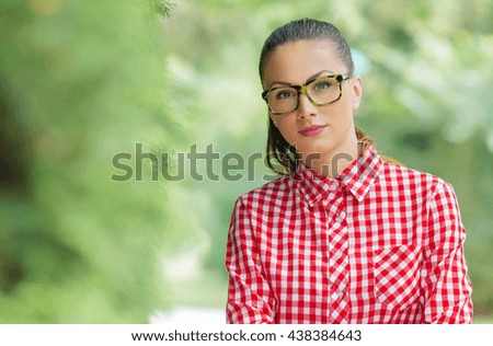Portrait of  young girl wearing spectacles. Outdoors, outside. Copyspace blurred green background