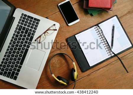Wood office desk table with laptop, smartphone, Top view,Layout of comfortable working space on wooden, internet laptop headphone phone notepad pen eyeglasses laying on it, busy business lifestyle.