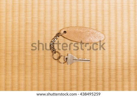 Metallic key with eclipse shaped wooden key chain on the Japanese Tatami mat  background 
