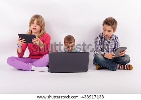 Screen addiction concept - sister and brother using tablets and their younger brother who is a baby using laptop