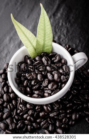 Coffee cup and coffee beans on black table